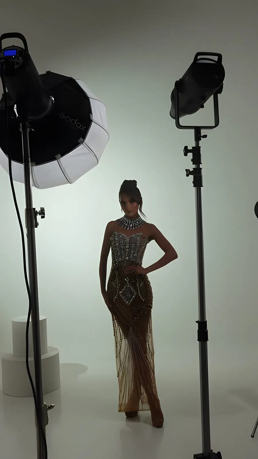 A candidate poses in a beaded gown during a studio photo shoot
